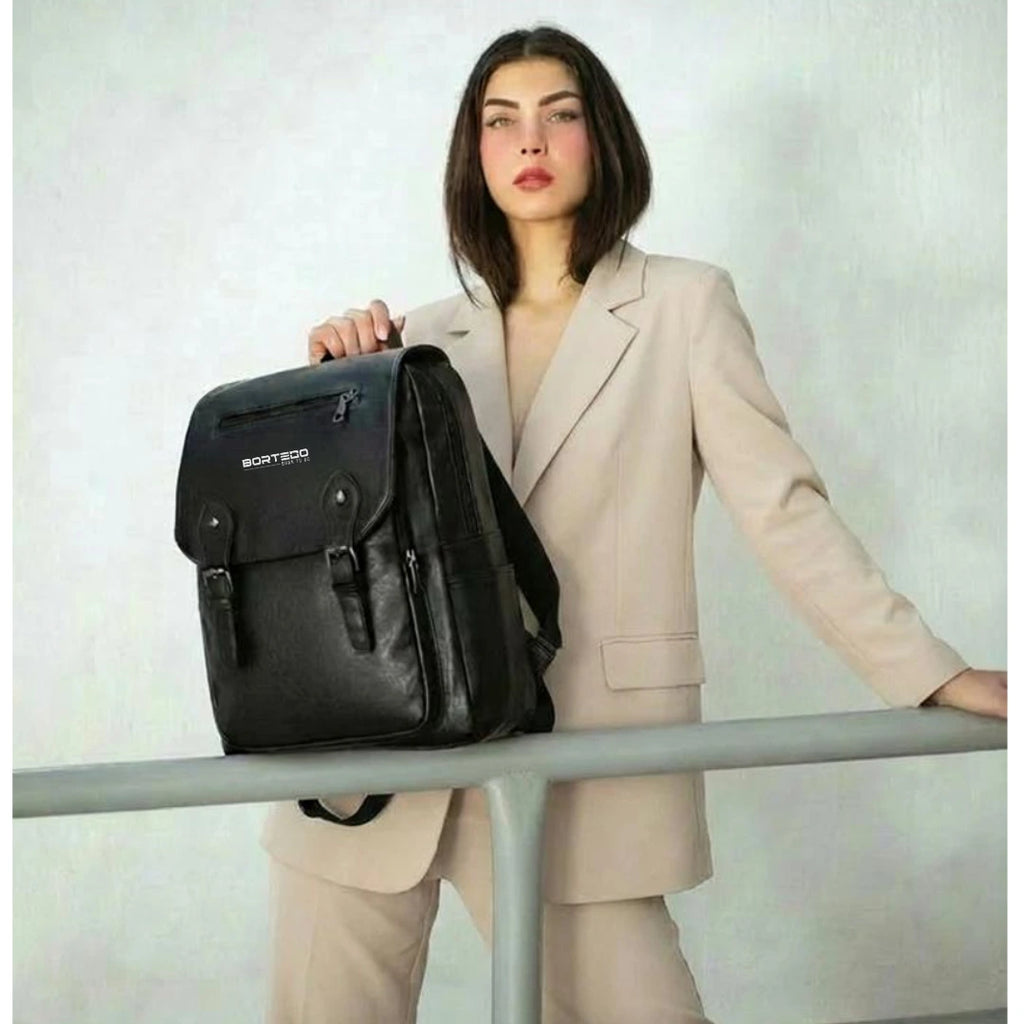 Woman in a beige suit holding a black backpack with a visible brand logo.