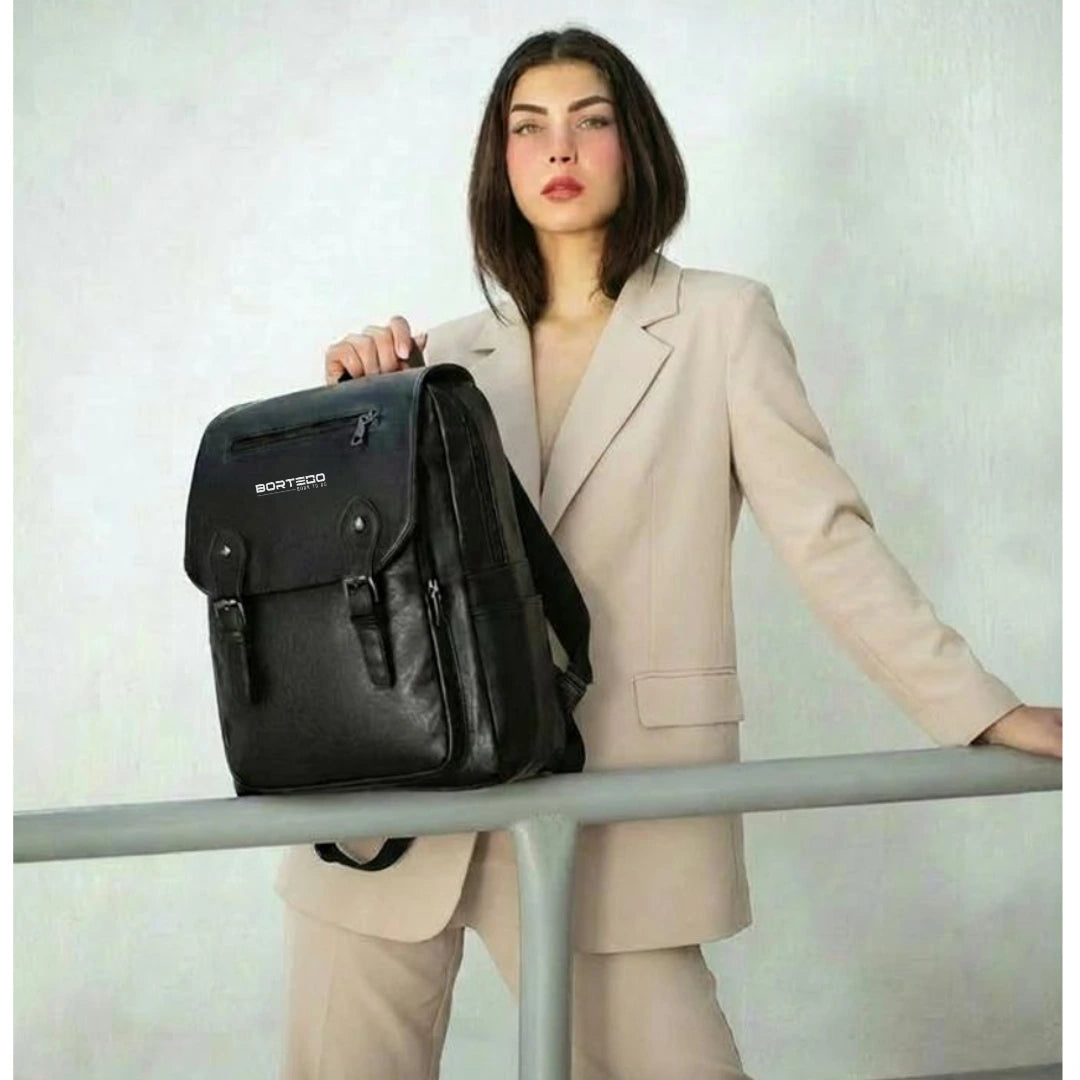 Woman in a beige suit holding a black backpack with a visible brand logo.