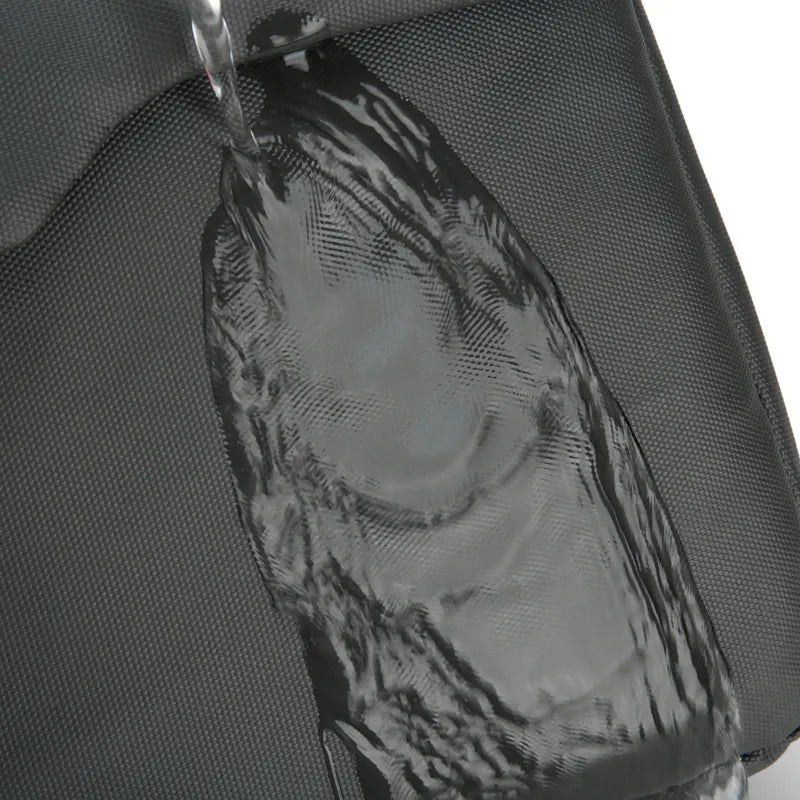 Close-up of water being poured onto a black textured waterproof bag, demonstrating its water-resistant property.