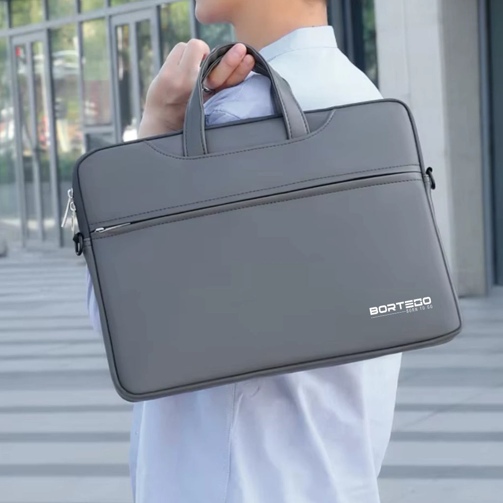 A gray laptop briefcase bag with top handles and a front zip pocket, carried over the shoulder of a person wearing a white shirt. The brand name 'BORTEGO' is printed in white on the lower right corner of the bag.