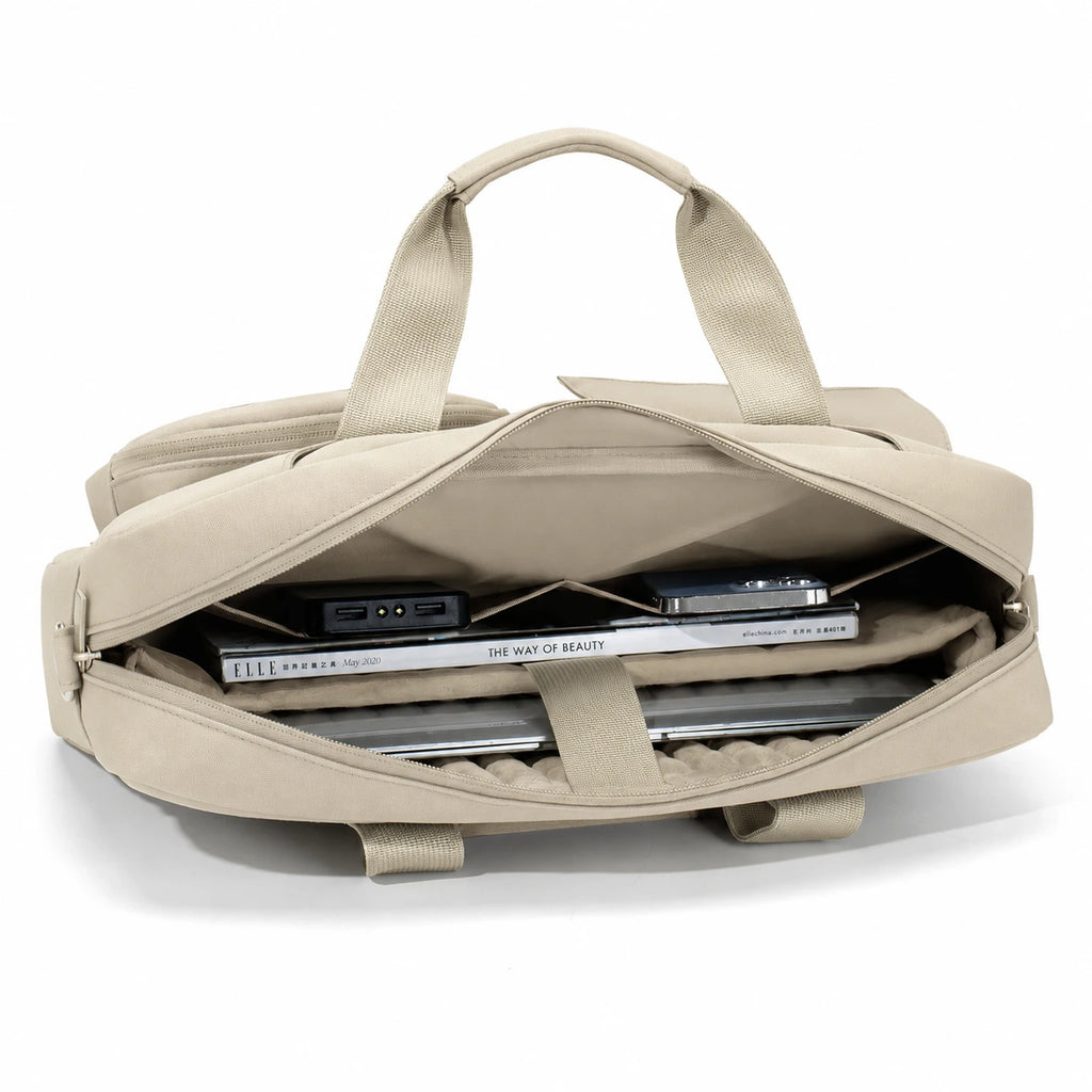 A beige canvas laptop backpack shown open, revealing a padded interior with a laptop, notebook, and accessories inside. The backpack has dual top handles and is photographed on a clean white background.