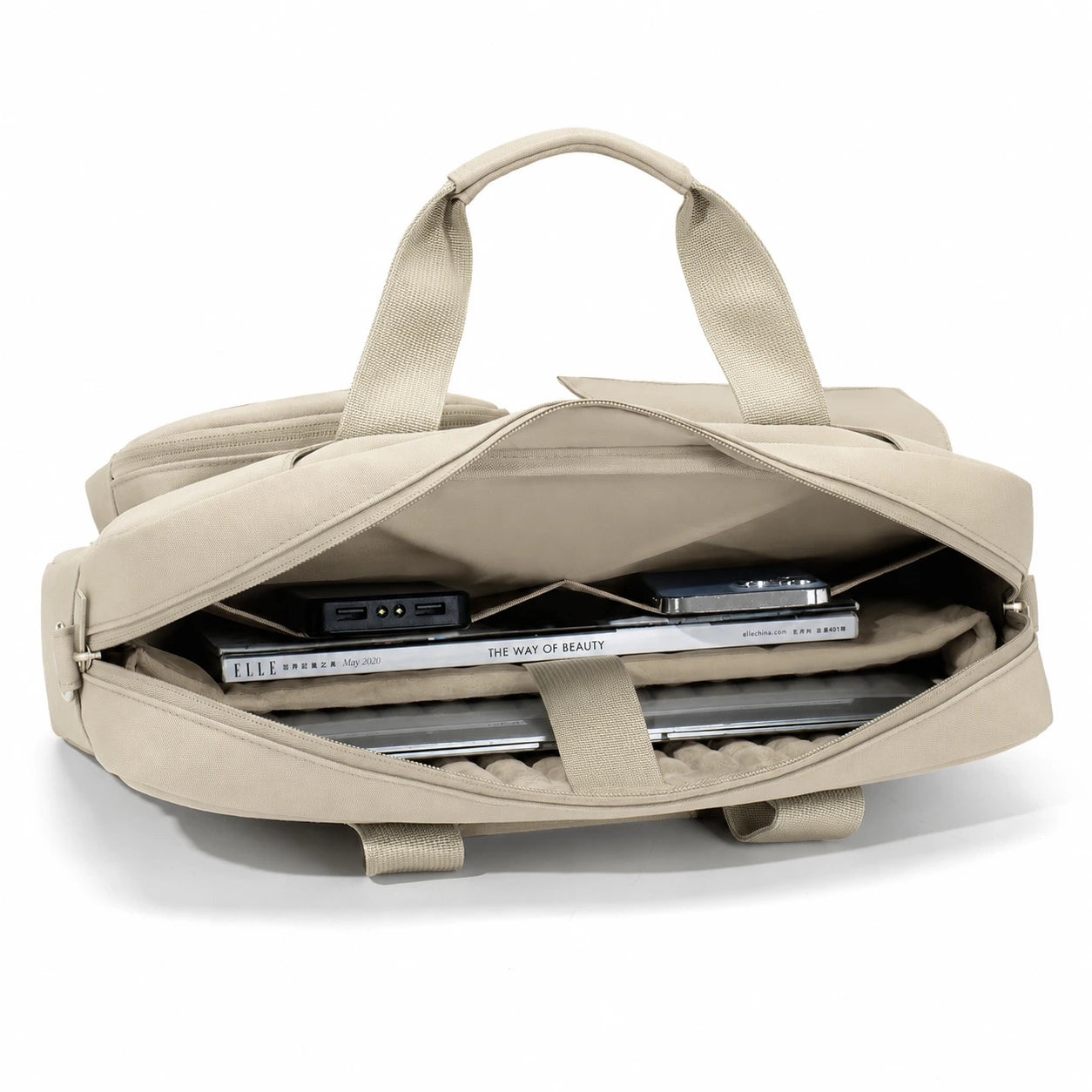 A beige canvas laptop backpack shown open, revealing a padded interior with a laptop, notebook, and accessories inside. The backpack has dual top handles and is photographed on a clean white background.