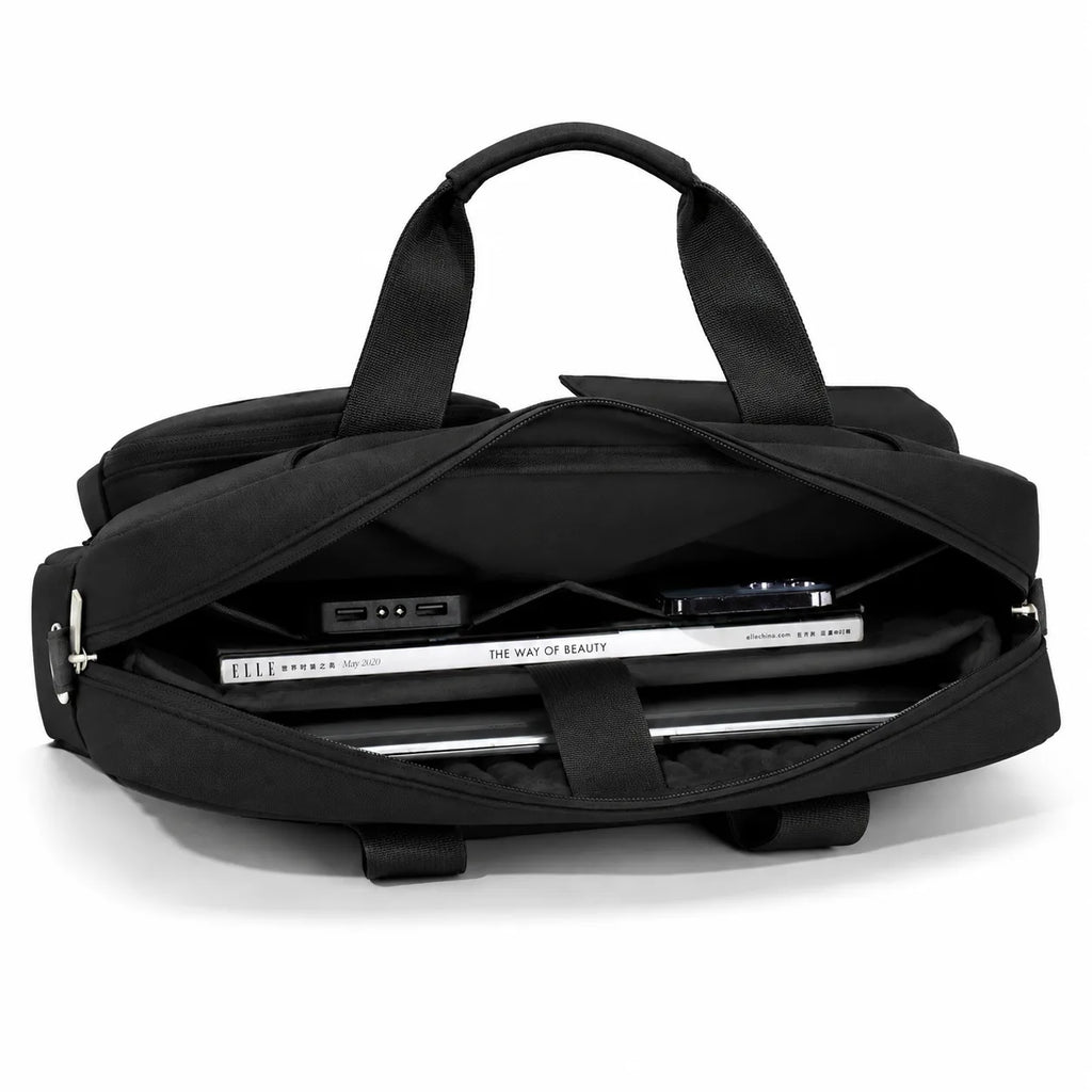 A black duffel bag shown open, with its handles extended and a laptop and accessories stored inside, photographed on a clean white background.