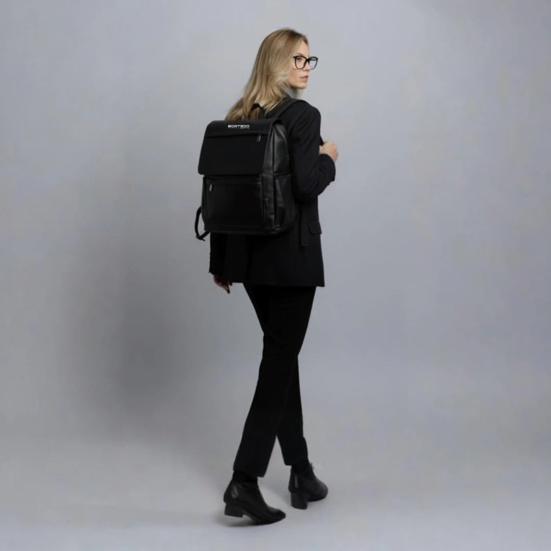 Person wearing a black backpack against a plain background