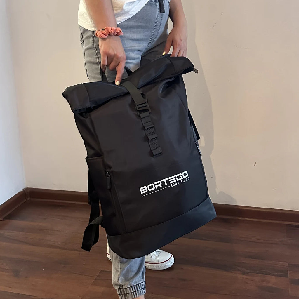Person holding a black backpack with 'Bortego' branding indoors.