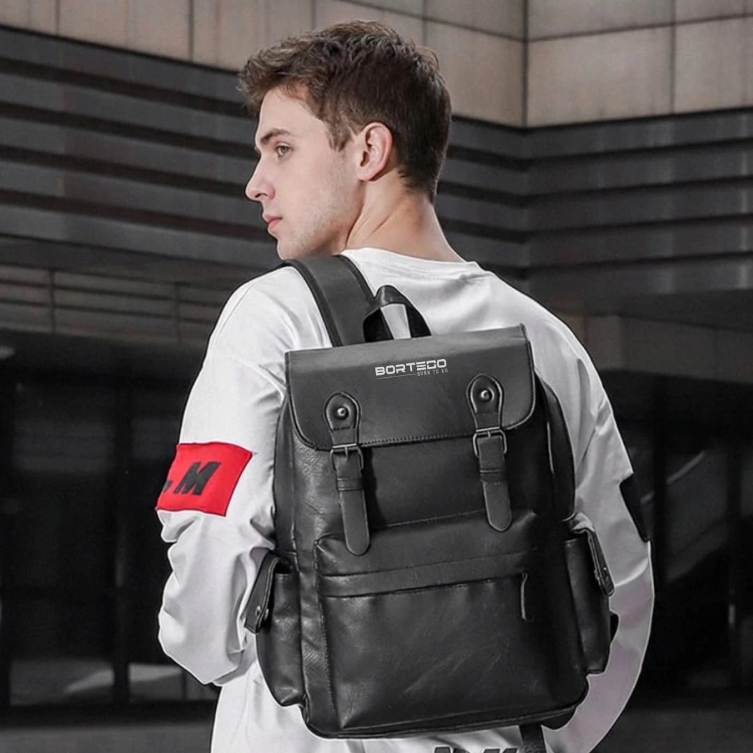 Man wearing a black backpack with a visible brand logo, standing in an urban setting.