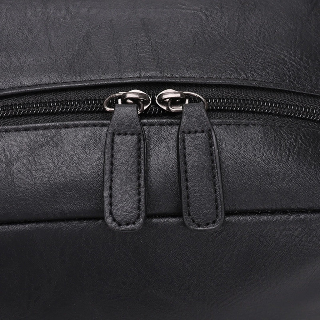 Close-up of a black leather bag with zipper details