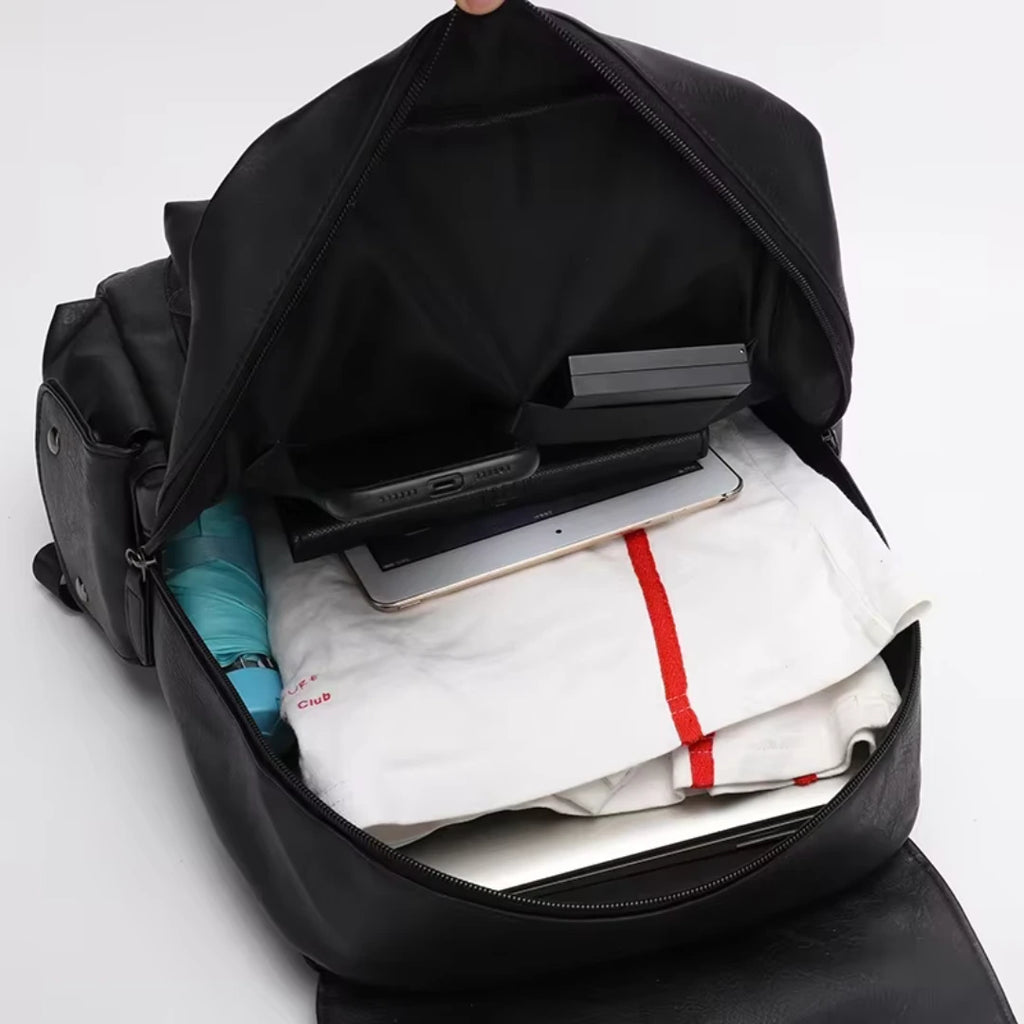 Black backpack with clothes and a tablet inside on a white background