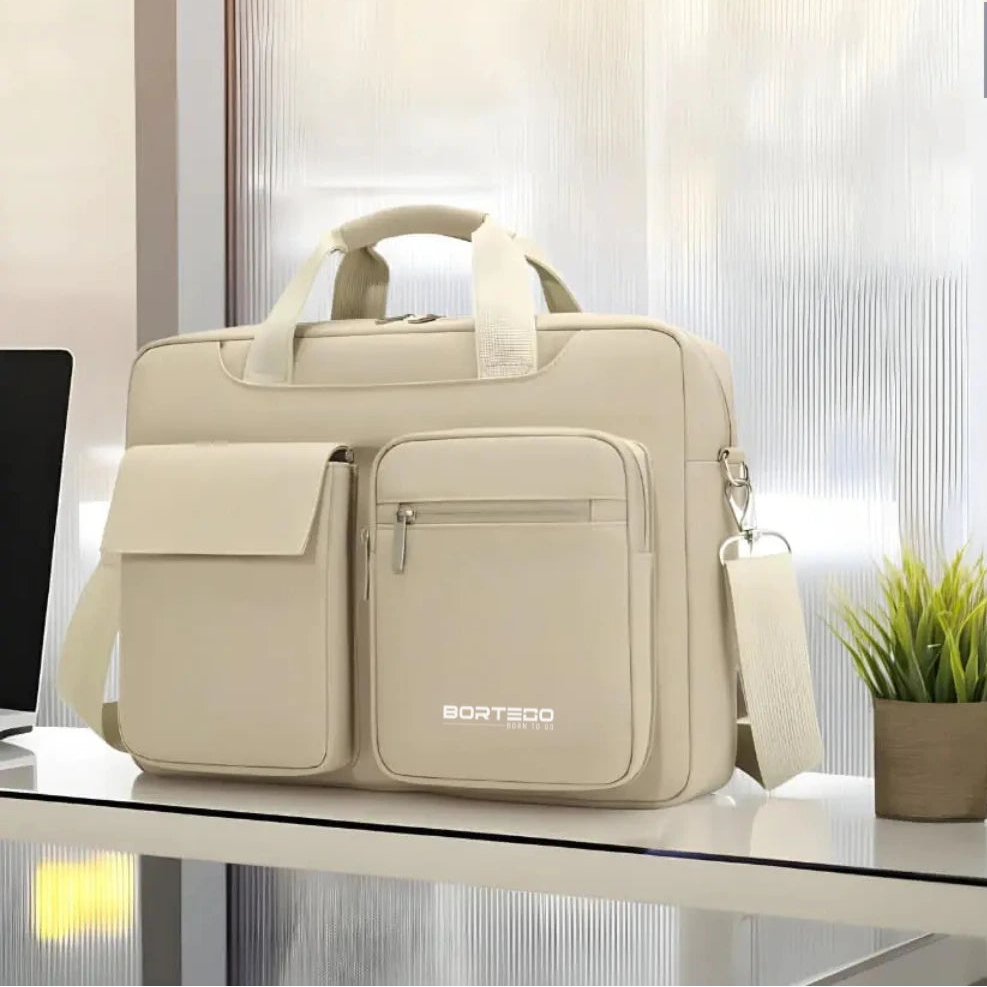 A light beige laptop briefcase with dual top handles, a front flap pocket, and a front zippered pocket featuring the BORTEGO logo, displayed on a glass desk with a small potted plant in the background.