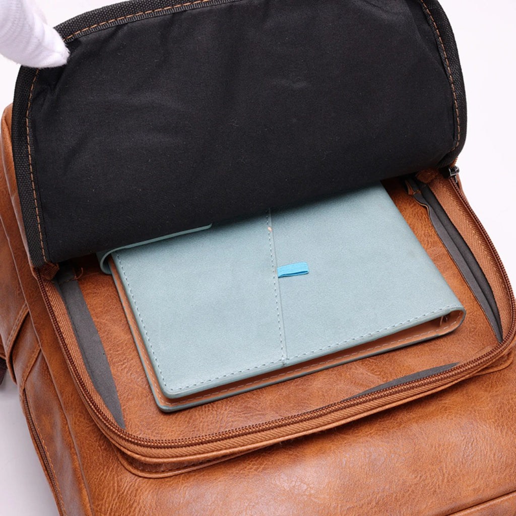 Brown leather backpack with a black roll-top compartment and a light blue wallet inside.