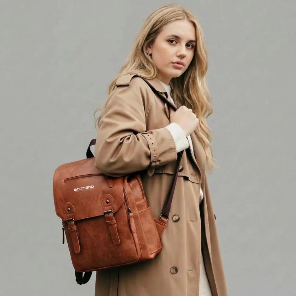 Woman holding a brown leather backpack against a gray background