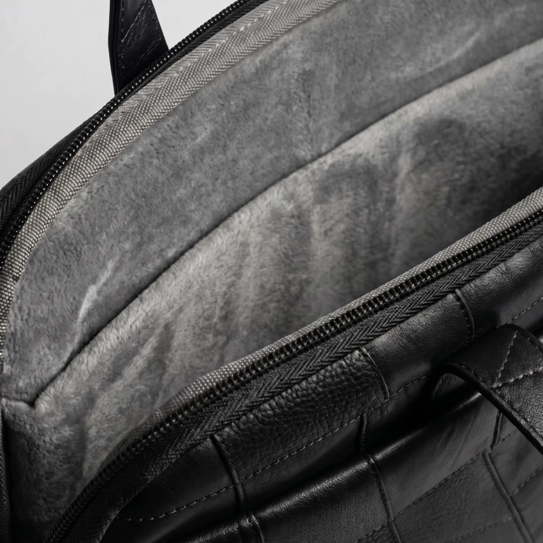 Close-up detail of a black leather bag showing the interior lining with a gray plush fleece insert and a zipper.
