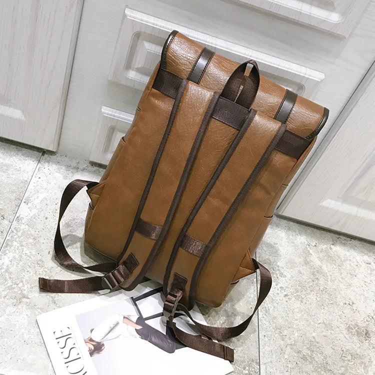 Brown leather backpack on a light gray floor with a magazine underneath