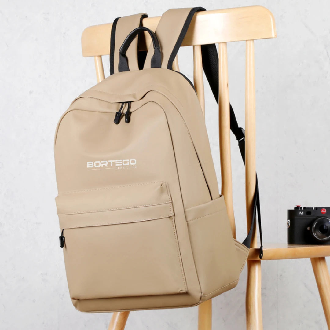 Beige backpack with 'Bortego' branding on a wooden chair against a light gray background