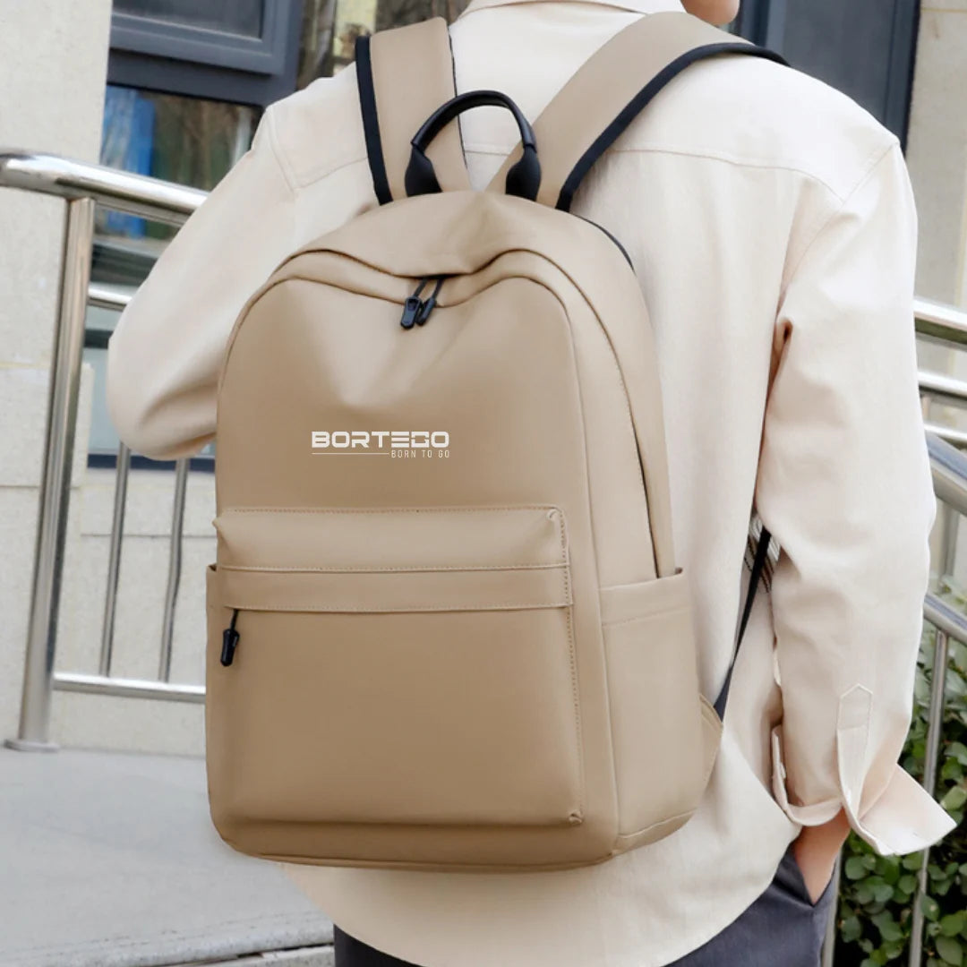Person wearing a beige backpack with 'Bortego' branding outdoors.