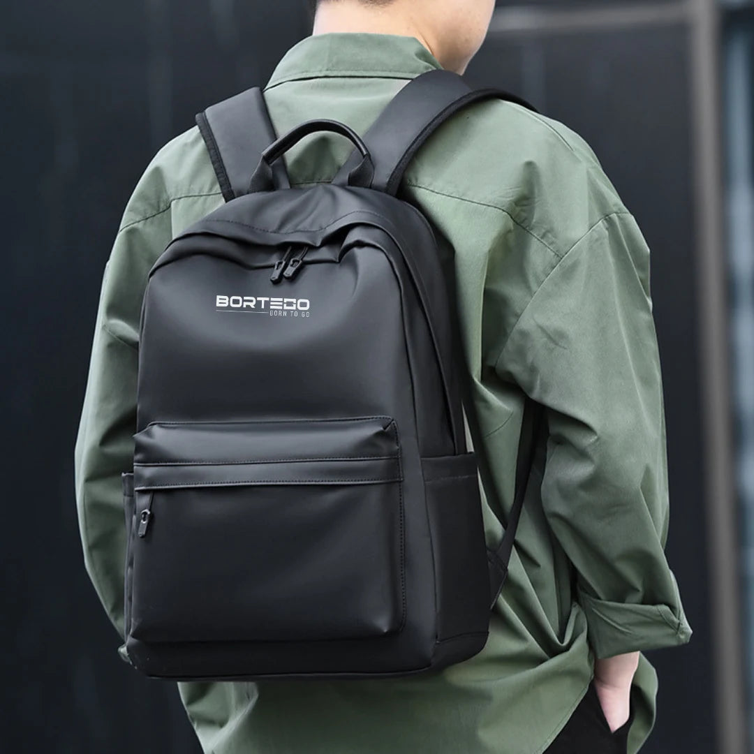 Person wearing a black backpack with 'Borteco' branding against a dark background