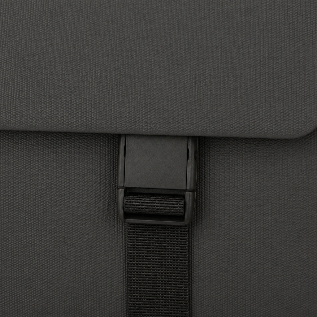 Close-up of a dark gray textured fabric bag with a black plastic buckle and black webbing strap.