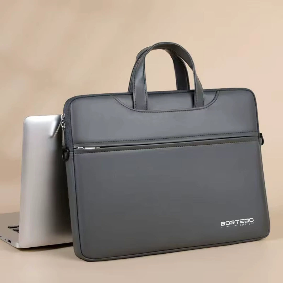 A dark gray BORTEGO laptop sleeve with dual top handles, shown standing upright next to a silver laptop on a beige background.
