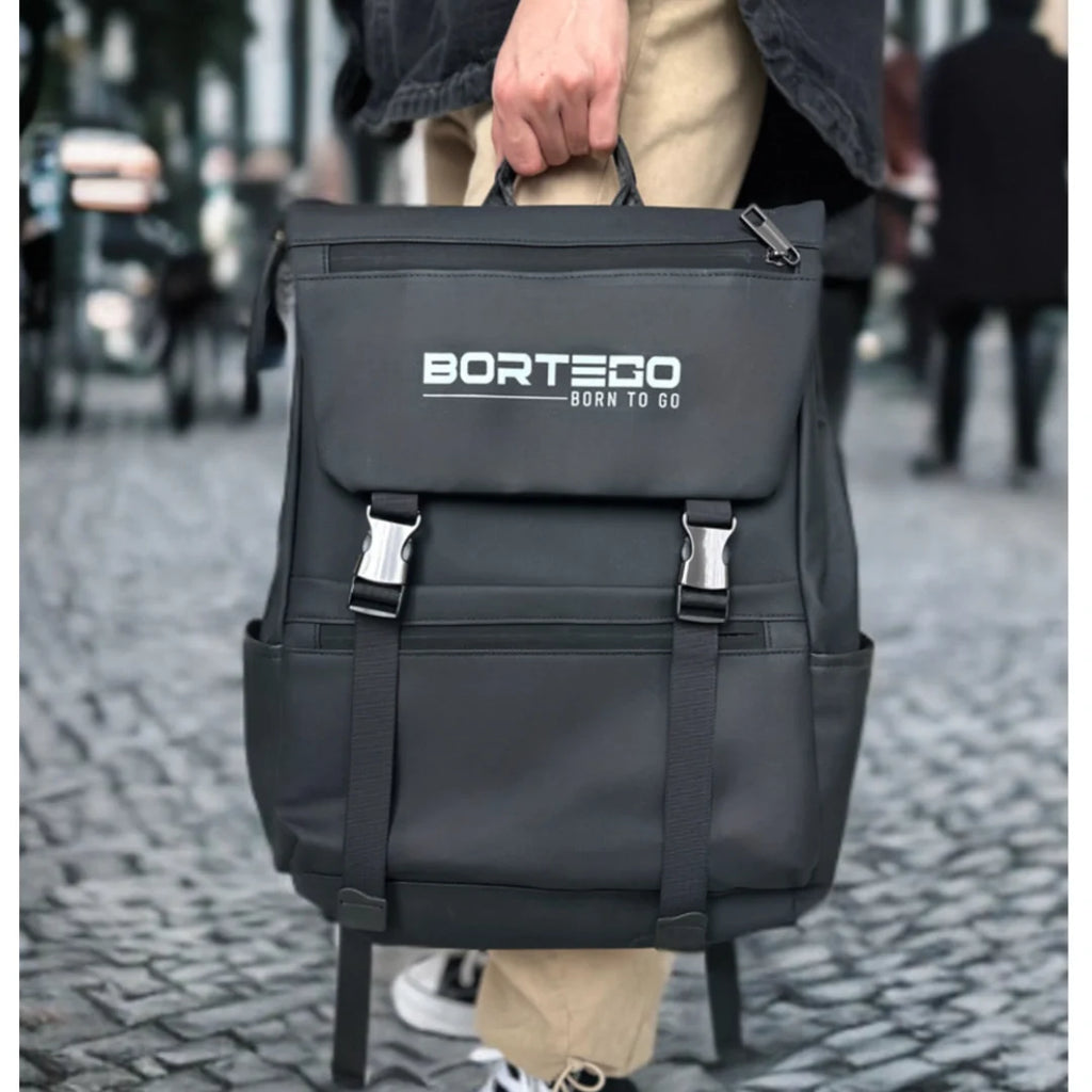Black backpack with 'Bortego' branding held by a person on a blurred street background