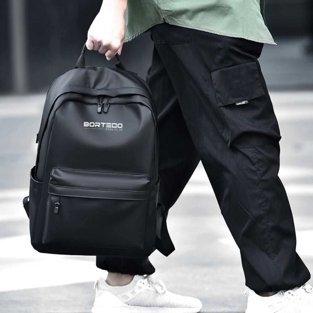 Person holding a black backpack with 'Borteco' branding on a blurred background