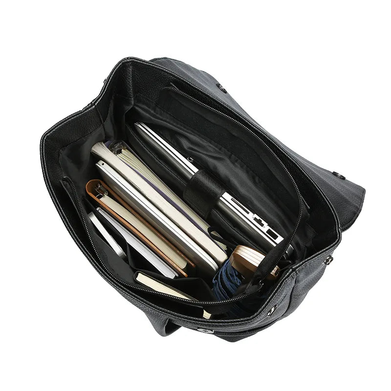 Black leather briefcase with silver and gold office supplies on a white background