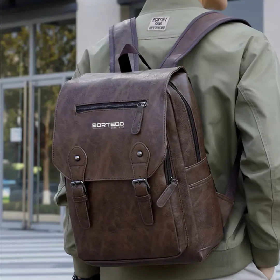 Person wearing a brown leather backpack with Borteco branding outdoors.