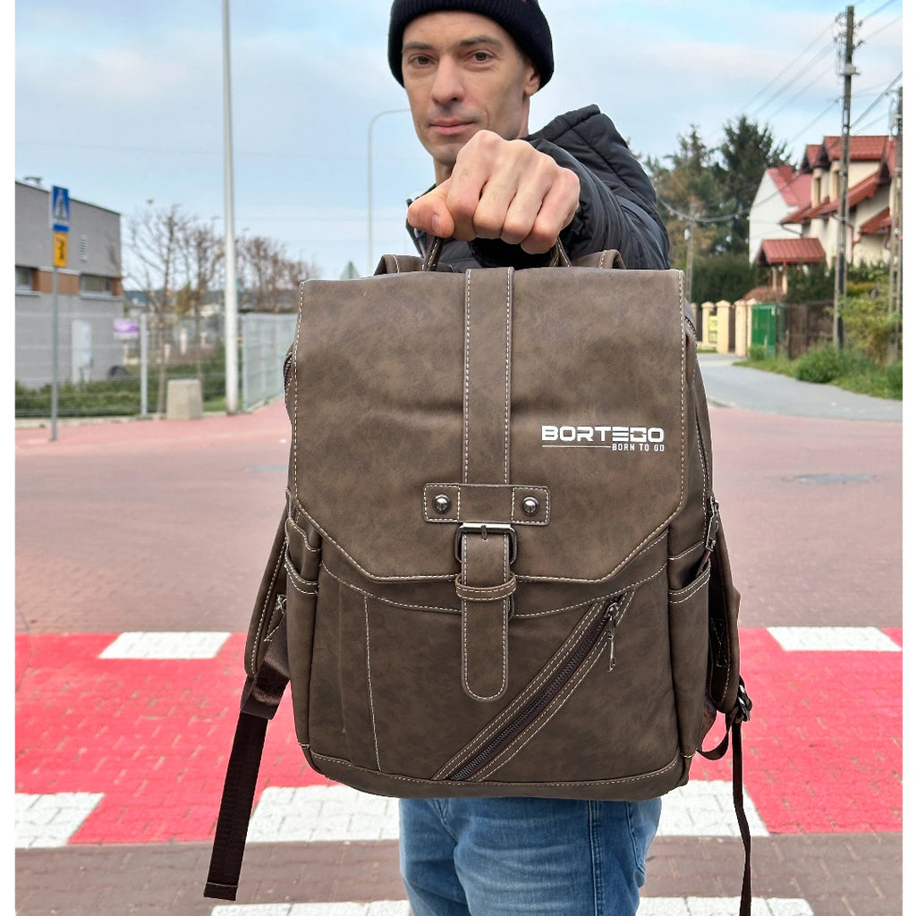 Man holding a brown backpack with 'Bortego' branding on a street.